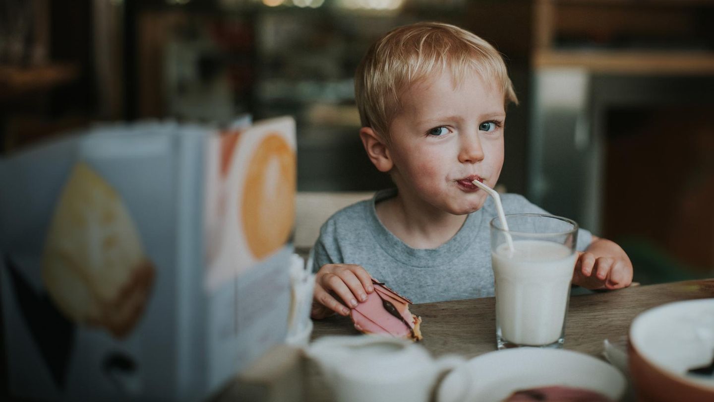 Ein Kind schlürft im Restaurant aus einem Glas Milch