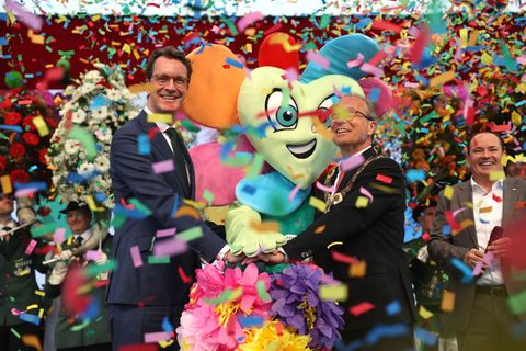 Moderator Wolfram Kons (r) steht neben Ministerpräsident Hendrik Wüst (l, CDU) und Bürgermeister Reiner Breuer (m, SPD) auf der