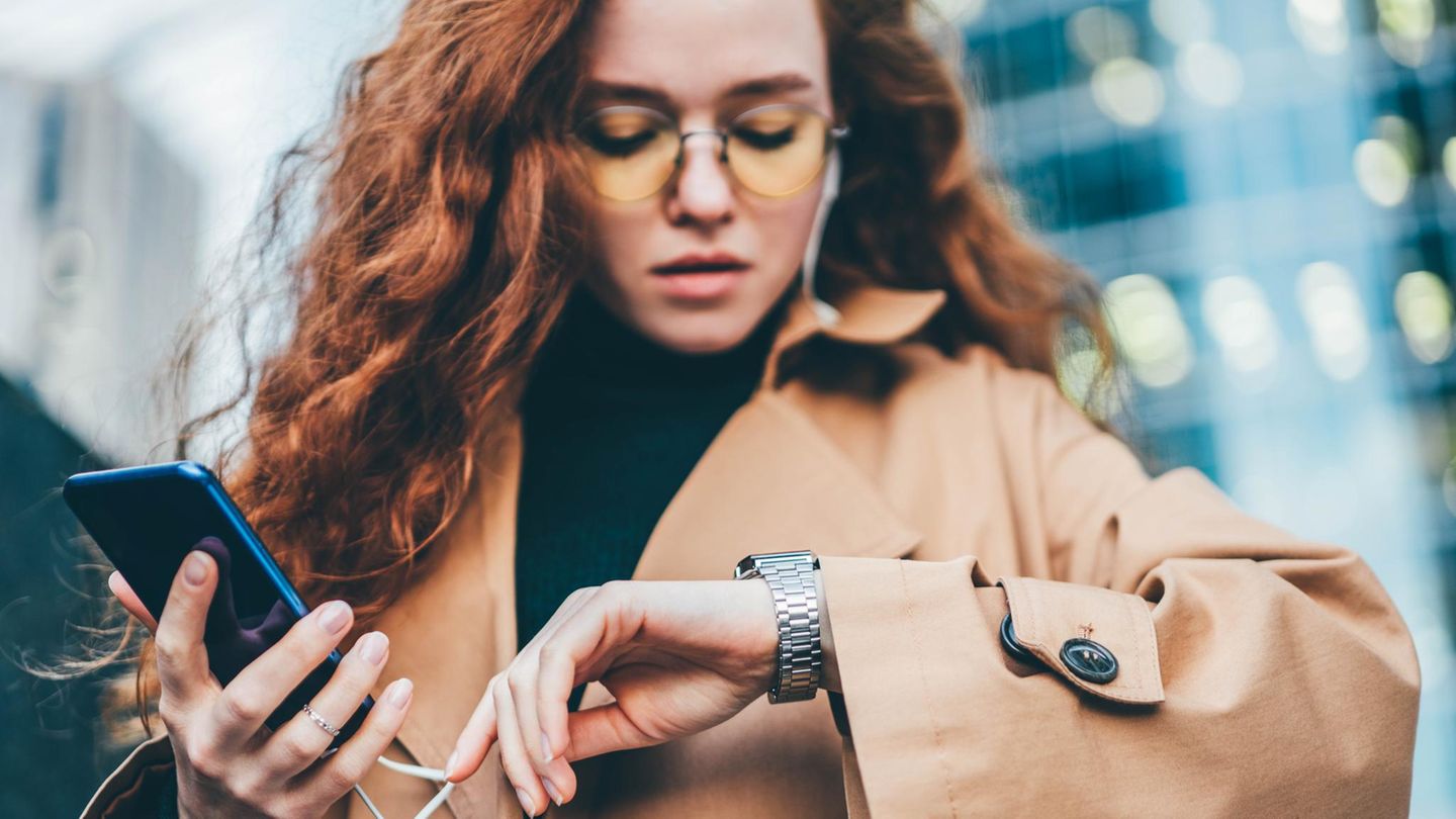 Eine Frau schaut auf die Uhr, während sie auf eine Antwort bei Whatsapp wartet