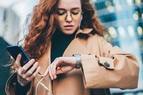 Eine Frau schaut auf die Uhr, während sie auf eine Antwort bei Whatsapp wartet