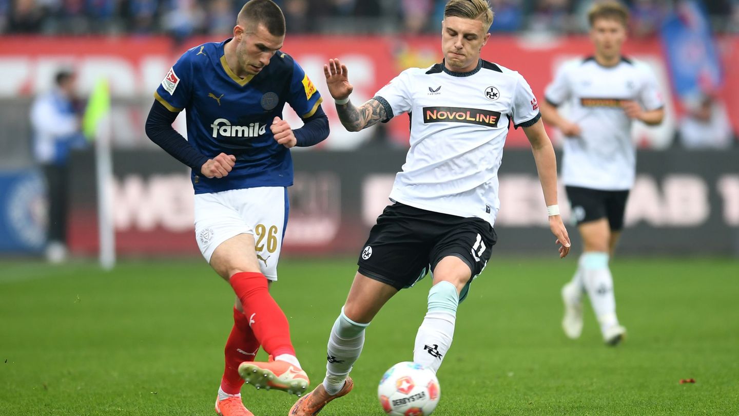 Kaiserslauterns Norman Bassette (r) stört den Kieler Torschützen David Zec. Foto: Daniel Bockwoldt/dpa