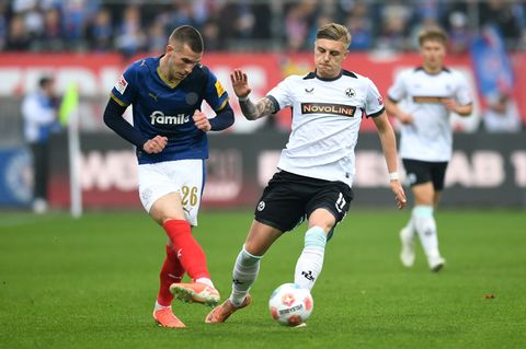 Kaiserslauterns Norman Bassette (r) stört den Kieler Torschützen David Zec. Foto: Daniel Bockwoldt/dpa