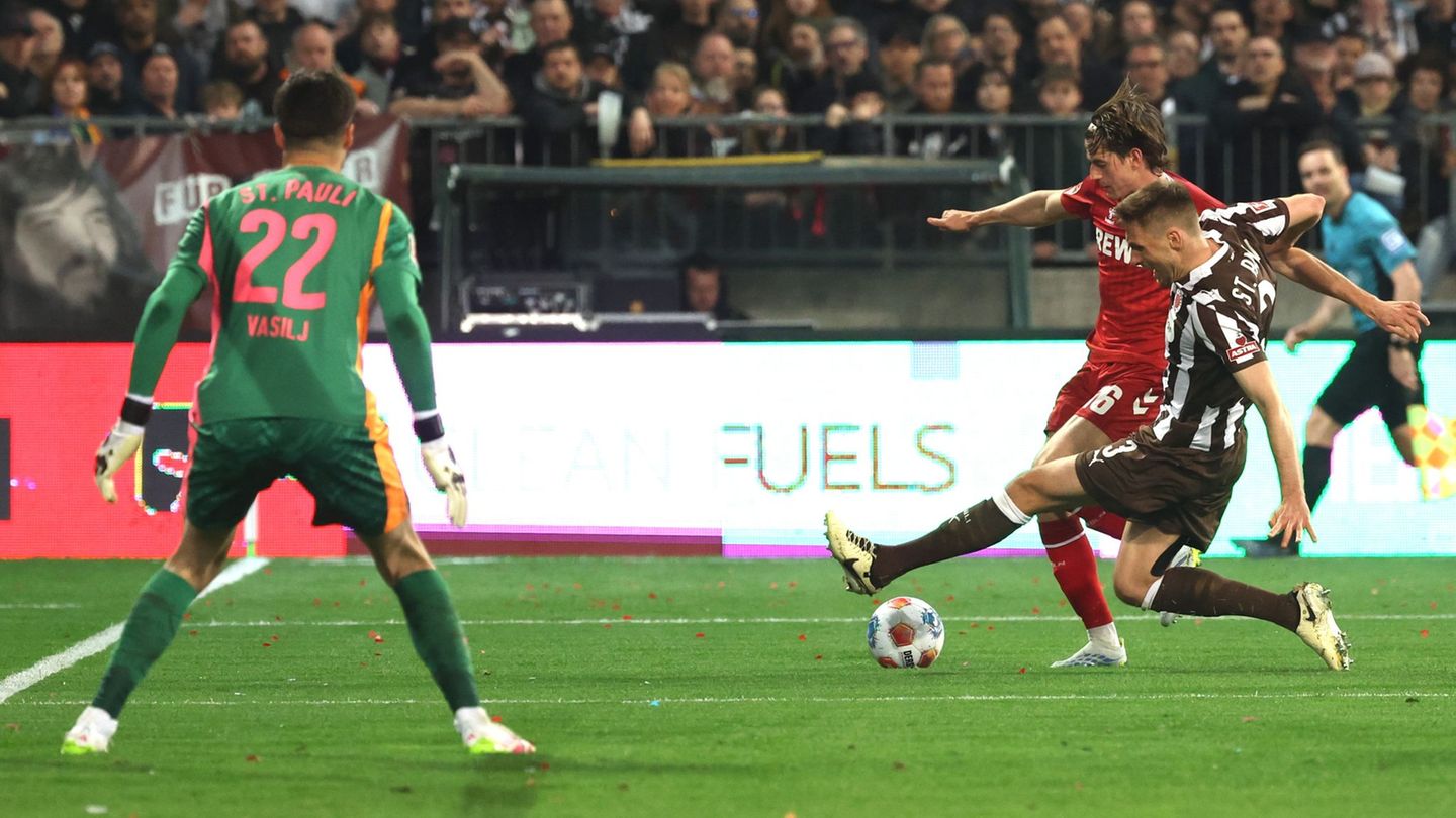 Die aus Sicht von Alexander Blessin strittige Szene vor dem Strafstoß: Kölns Jakub Kaminski (M,) und Karol Mets (FC St. Pauli) k