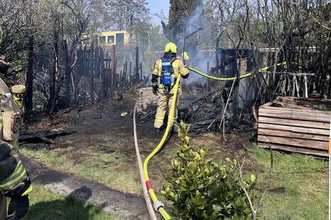 Einsatzkräfte der Feuerwehr löschen den Brand zweier Gartenhäuser. (Handout) Foto: ---/Berliner Feuerwehr/dpa