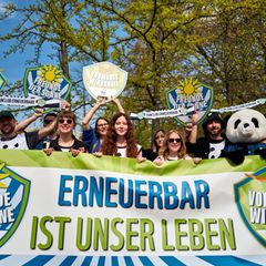 Demonstrierende halten ein Banner und Schilder in die Höhe, darunter eine Person im Pandakostüm. Foto: Michael Ukas/dpa