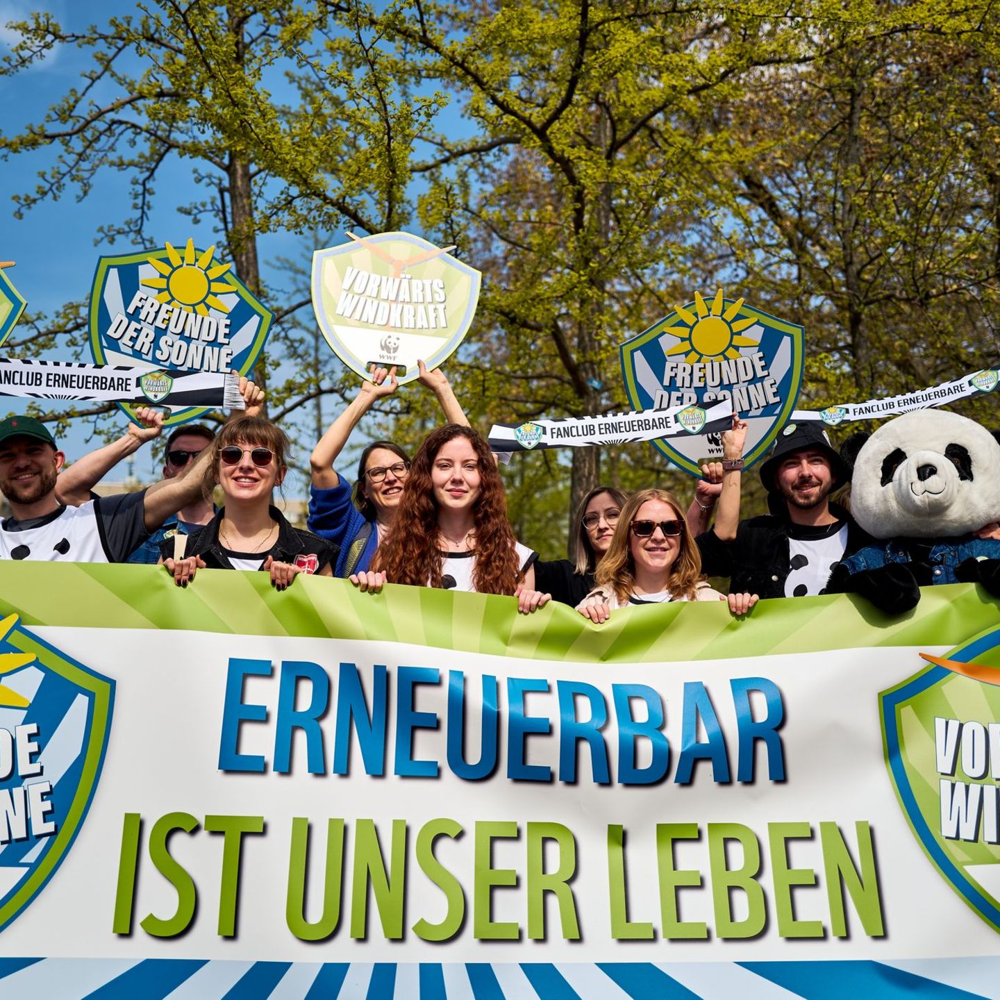Demonstrierende halten ein Banner und Schilder in die Höhe, darunter eine Person im Pandakostüm. Foto: Michael Ukas/dpa
