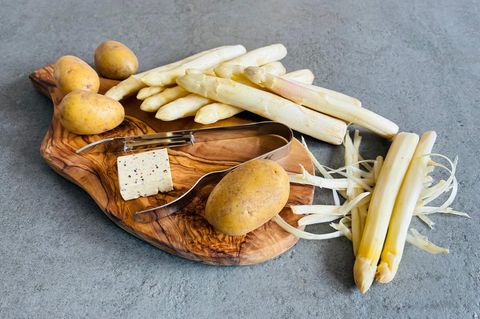 Spargel, Kartoffel, Butter, Spargelschäler auf einem Brettchen