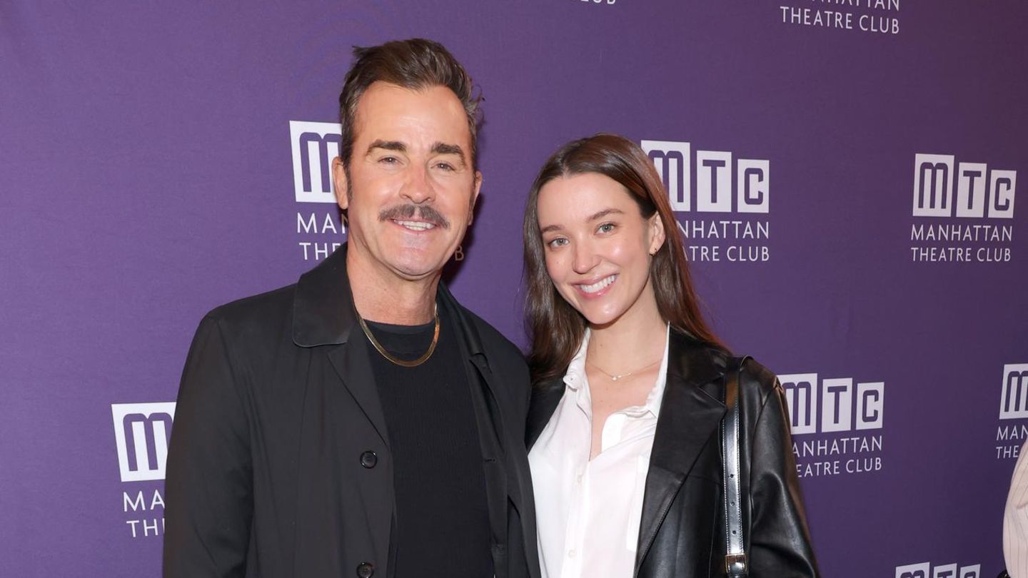 Justin Theroux und Nicole Brydon Bloom vor einer violetten Werbewand