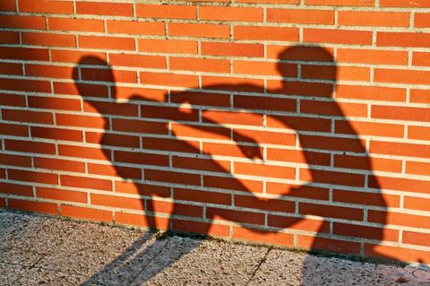 Die Schatten zweier prügelnder Kinder fallen auf eine Backsteinmauer: Symbolbild für Kriminalstatistik