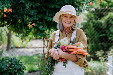 Rentnerin im eigenen Garten mit Gemüse in der Hand – muss mit wenig Rente auskommen