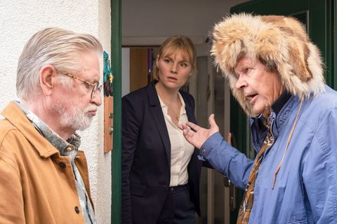 Der alte Griesgram (Heikki Kinnunen, rechts) drängt seinen Bruder Tarmo (Kari Väänänen), auf dem Weg zu dem roten Escort einen Zwischenstopp bei Tarmos entfremdeter Tochter Maria (Rosalie Thomass) einzulegen.