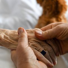 Eine Frau hält die Hand einer älteren Frau