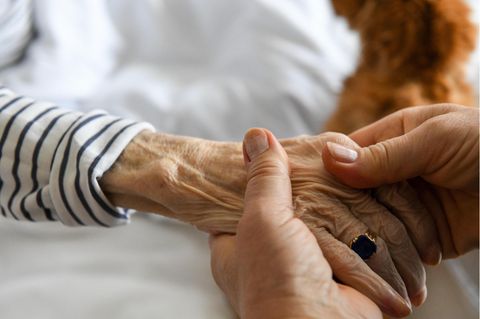 Eine Frau hält die Hand einer älteren Frau