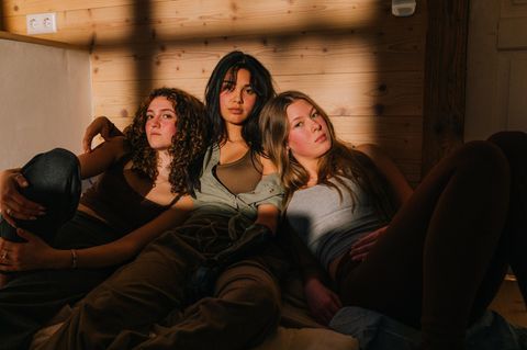 Drei junge Leute der Generation Z sitzen entspannt auf dem Boden und blicken in die Kamera