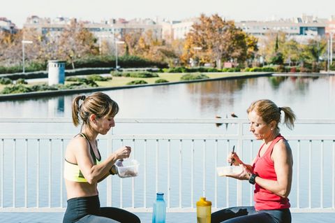 Kohlenhydrate essen: Zwei Frauen in Sportbekleidung sitzen an einem See