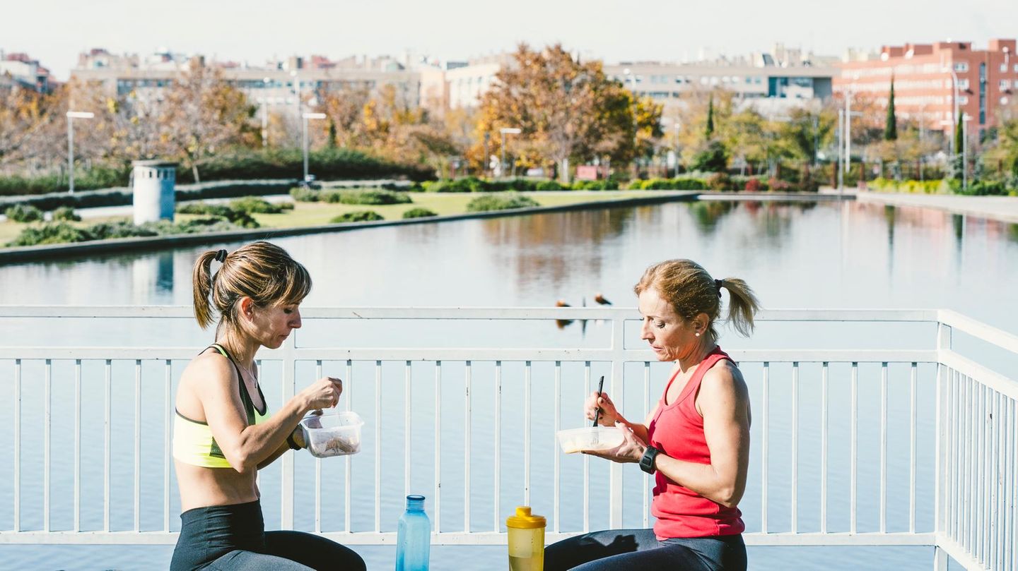 Kohlenhydrate essen: Zwei Frauen in Sportbekleidung sitzen an einem See