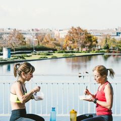 Kohlenhydrate essen: Zwei Frauen in Sportbekleidung sitzen an einem See