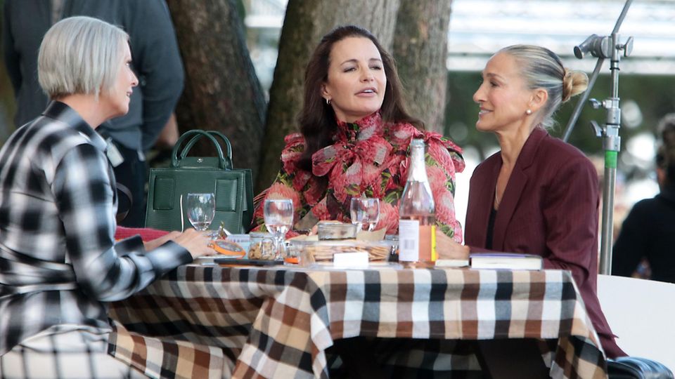 Cynthia Nixon, Kristin Davis, Sarah Jessica Parker sitzen an einem Tisch und unterhalten sich