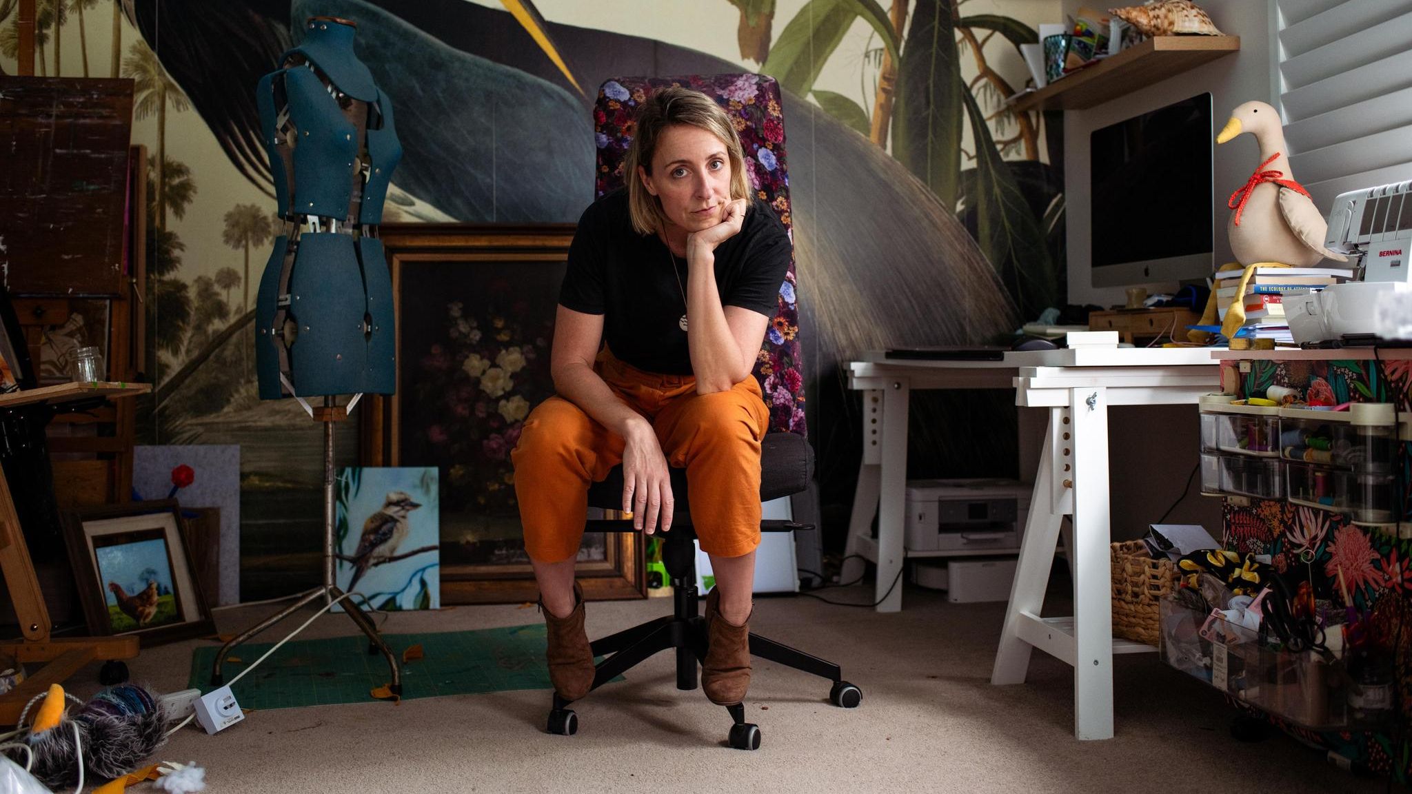 Candice Fox auf einem Bürostuhl umgeben Bildern, einem Schreibtisch und einer Schneiderpuppe