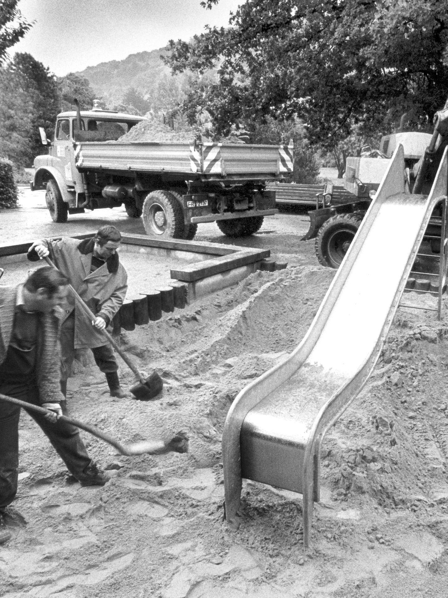 Zwei Männer mit Schaufeln auf einem Spielplatz