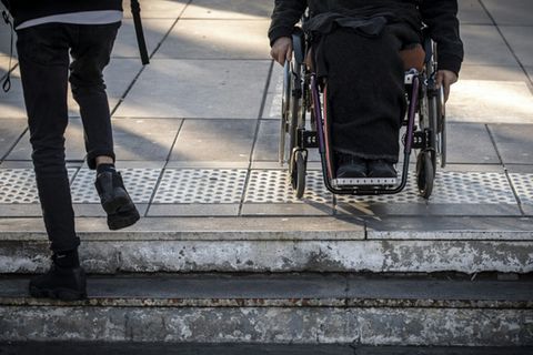 Mann mit Rollstuhl an Treppe