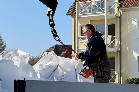 Unternehmer Fred Babbel lädt mit Sand gefüllte Big Bags von einem Lkw am Hafen von Kirchdorf ab