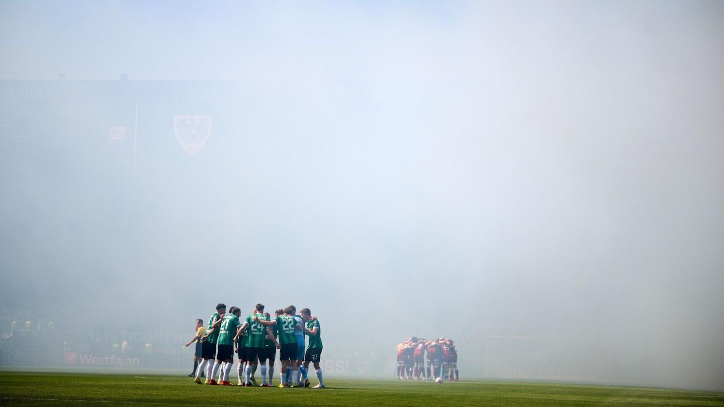 Münster, Deutschland. Erzrivalen im Duell: Arminia Bielefeld tritt in der 2. Bundesliga beim Tabellenletzten Preußen Münster an. Die Pyrotechnik der Fans hüllt das Stadion in Rauch.