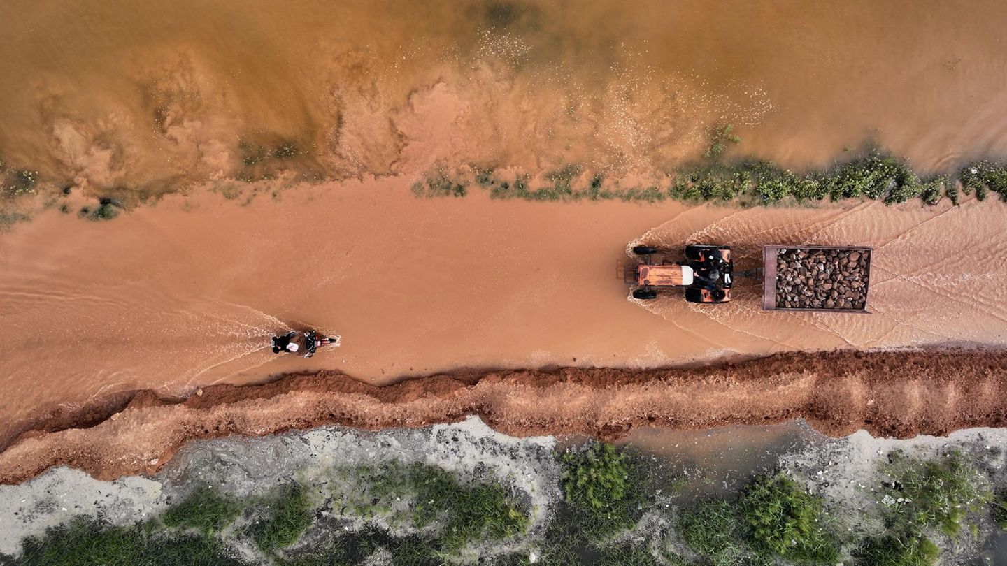 Abu al-Duhur, Syrien. Ein Traktor und ein Motorrad bahnen sich ihren Weg durch das schlammige Hochwasser auf einer Straße. Schwere Regenfälle ließen den Wasserstand des Al-Siha-Damms ansteigen. Betroffen waren nahe gelegene Dörfer und Ackerland im Nordwesten des Landes.