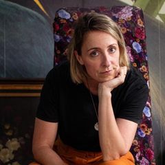 Candice Fox auf einem Bürostuhl umgeben Bildern, einem Schreibtisch und einer Schneiderpuppe