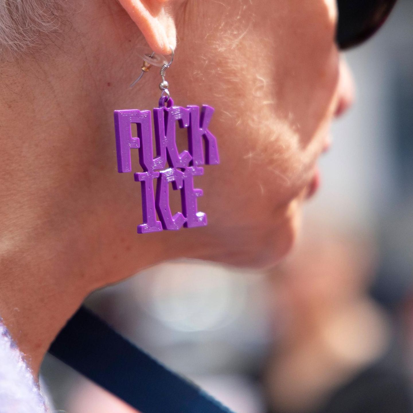 „Fuck ICE“ steht auf dem Ohrring einer Demo-Teilnehmerin in den USA