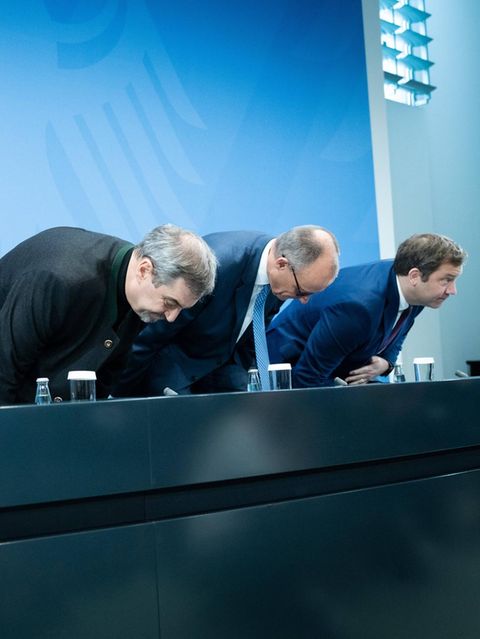 Markus Söder, Friedrich Merz und Lars Klingbeil setzen sich auf Stühle