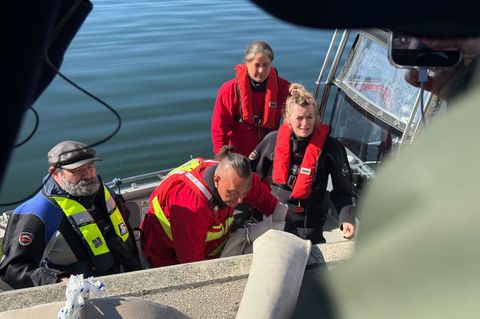 Helfer besteigen ein Boot, um zum Wal hinauszufahren. Foto: Helena Dolderer/dpa