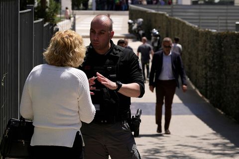 Ein Polizist spricht mit einer Frau vor einem Gerichtsgebäude in Athen