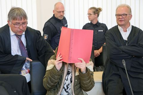 Die Angeklagte sitzt mit Aktendeckel vor dem Gesicht zwischen ihren Verteidigern Andreas Ohm (l-r) und Thomas Löcker. Foto: Bern