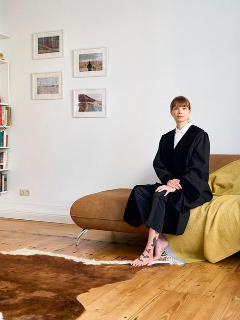 Ein Porträt von einer Frau, in "Uniform", die auf einem Sofa zuhause sitzt