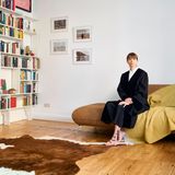 Ein Porträt von einer Frau, in "Uniform", die auf einem Sofa zuhause sitzt