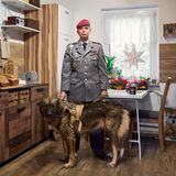 Ein Porträt von einer Frau in Uniform in ihrer Küche mit Hund