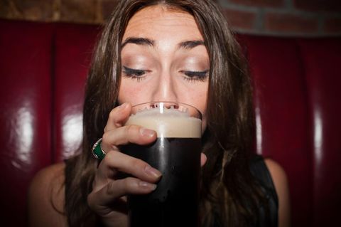 Eine junge Frau sitzt in einem Pub und trinkt ein Guinnes