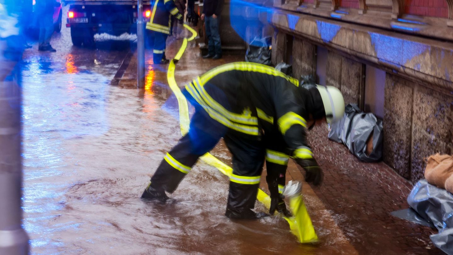 Ein Feuerwehr-Mitarbeiter verlegt einen Schlauch, um Hochwasser in Flensburg abzupumpen. (Archivbild) Foto: Frank Molter/dpa