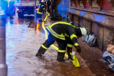 Ein Feuerwehr-Mitarbeiter verlegt einen Schlauch, um Hochwasser in Flensburg abzupumpen. (Archivbild) Foto: Frank Molter/dpa