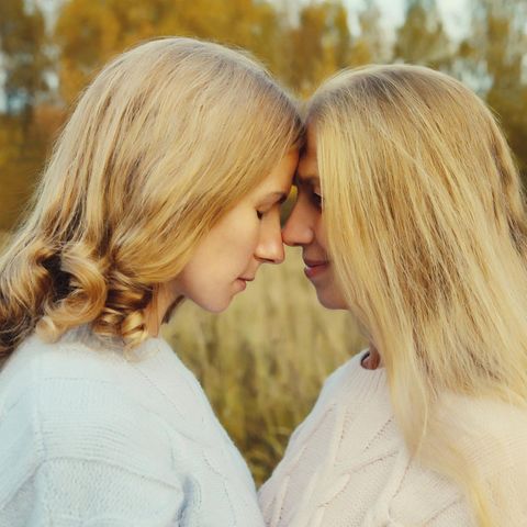 Schlankheitswahn: Mutter und Tochter stehen in der Natur und lehnen die Stirn aneinander