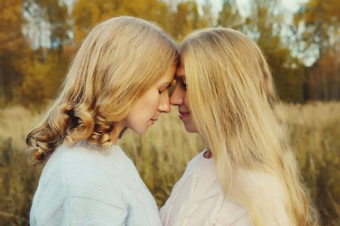 Schlankheitswahn: Mutter und Tochter stehen in der Natur und lehnen die Stirn aneinander