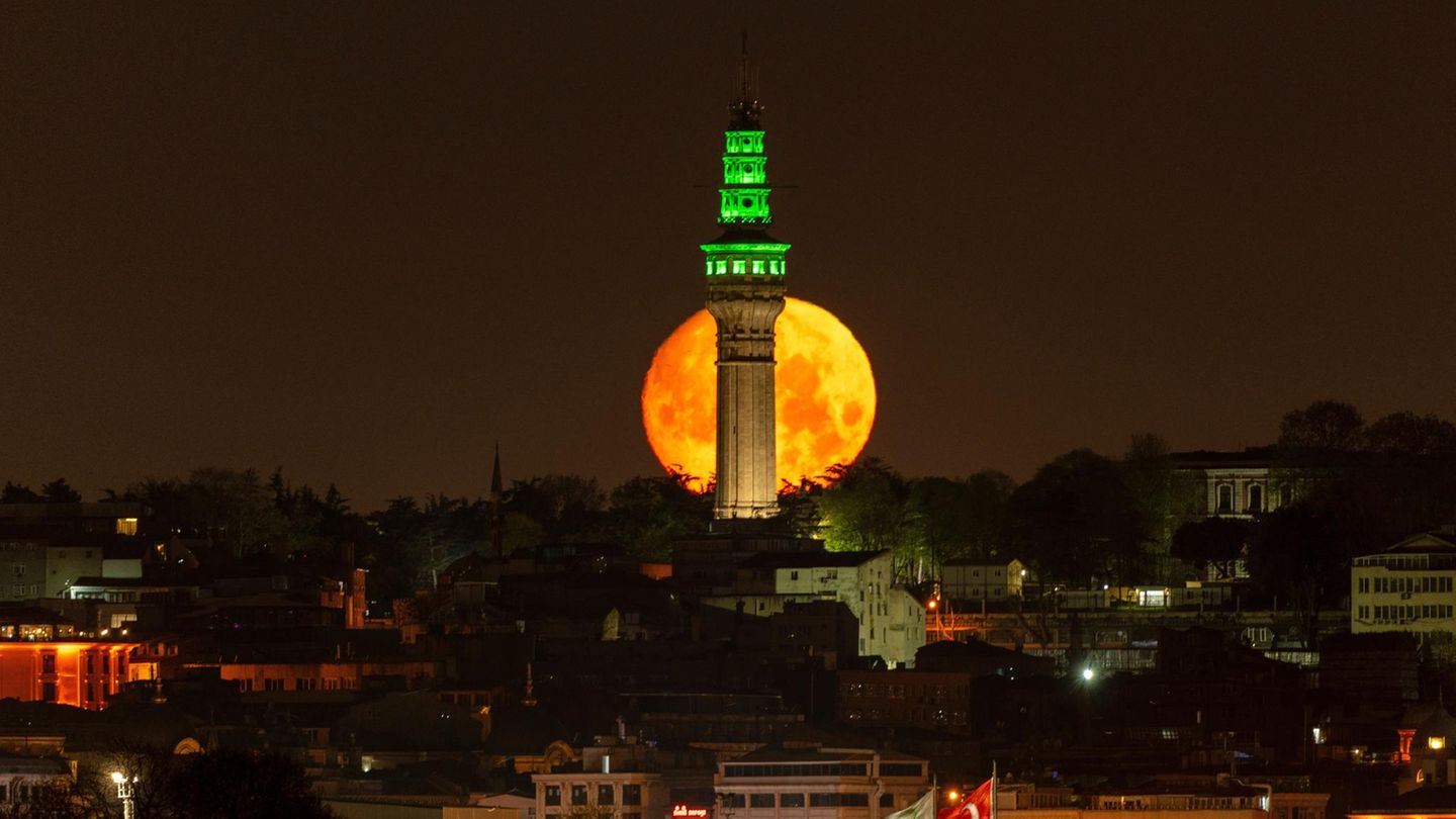Istanbul, Türkei. Der Vollmond, auch bekannt als Blumenmond, geht am Morgen hinter dem Beyazit-Turm unter.