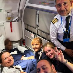 Die Crew eines Flugzeugs lächelt für ein Selfie mit der frisch gebackenen Mutter