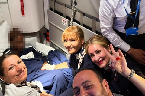 Die Crew eines Flugzeugs lächelt für ein Selfie mit der frisch gebackenen Mutter