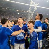 Das Team feiert mit einer Bierdusche auf dem Platz.