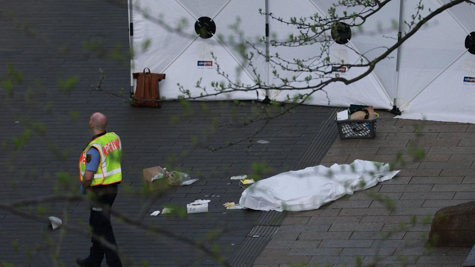 Ein Polizist steht neben einer abgedeckten Leiche an der Stelle in Leipzig,
