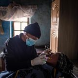 Eine Zahnärztin mit Schutzmaske lehnt sich über eine Patientin