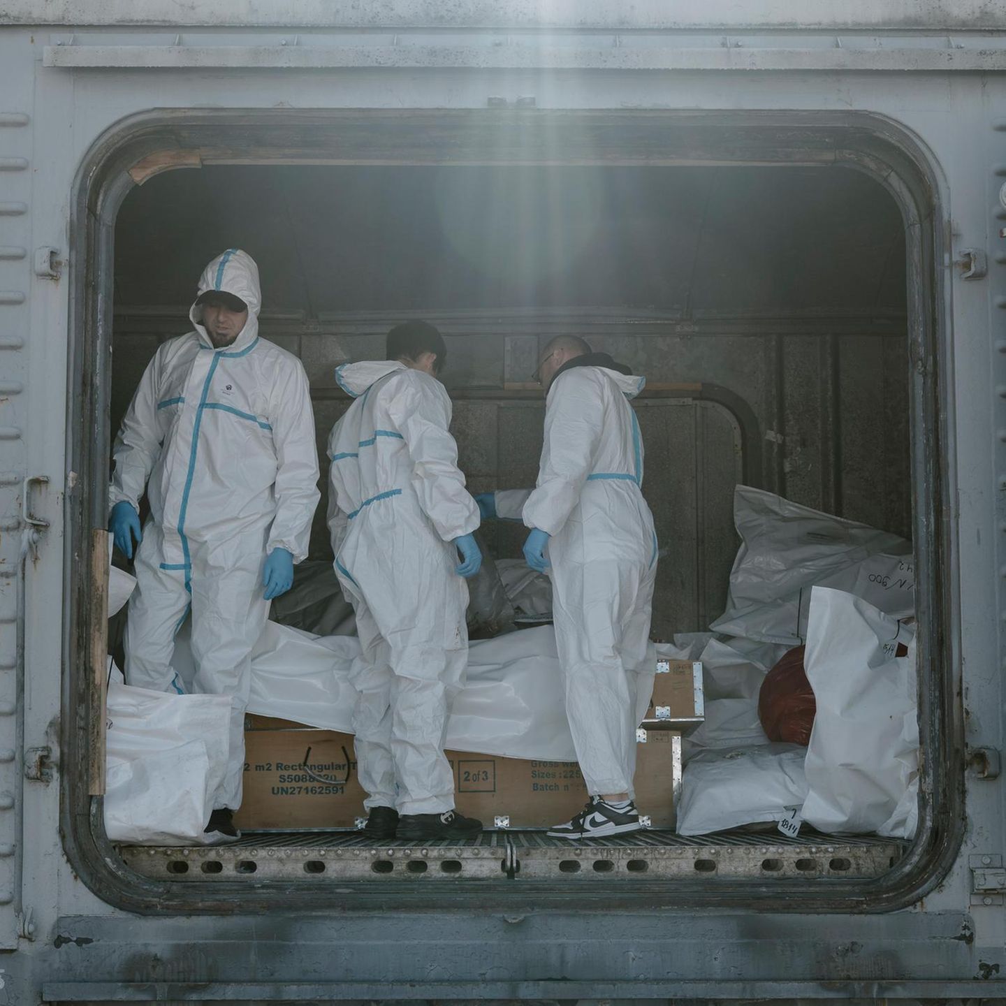 Forensiker in Schutzanzügen in Odessa, Ukraine, hinter ihnen Leichensäcke