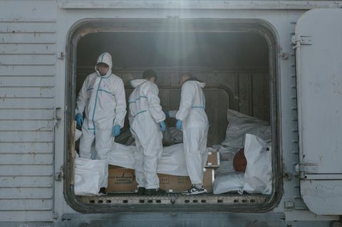 Forensiker in Schutzanzügen in Odessa, Ukraine, hinter ihnen Leichensäcke